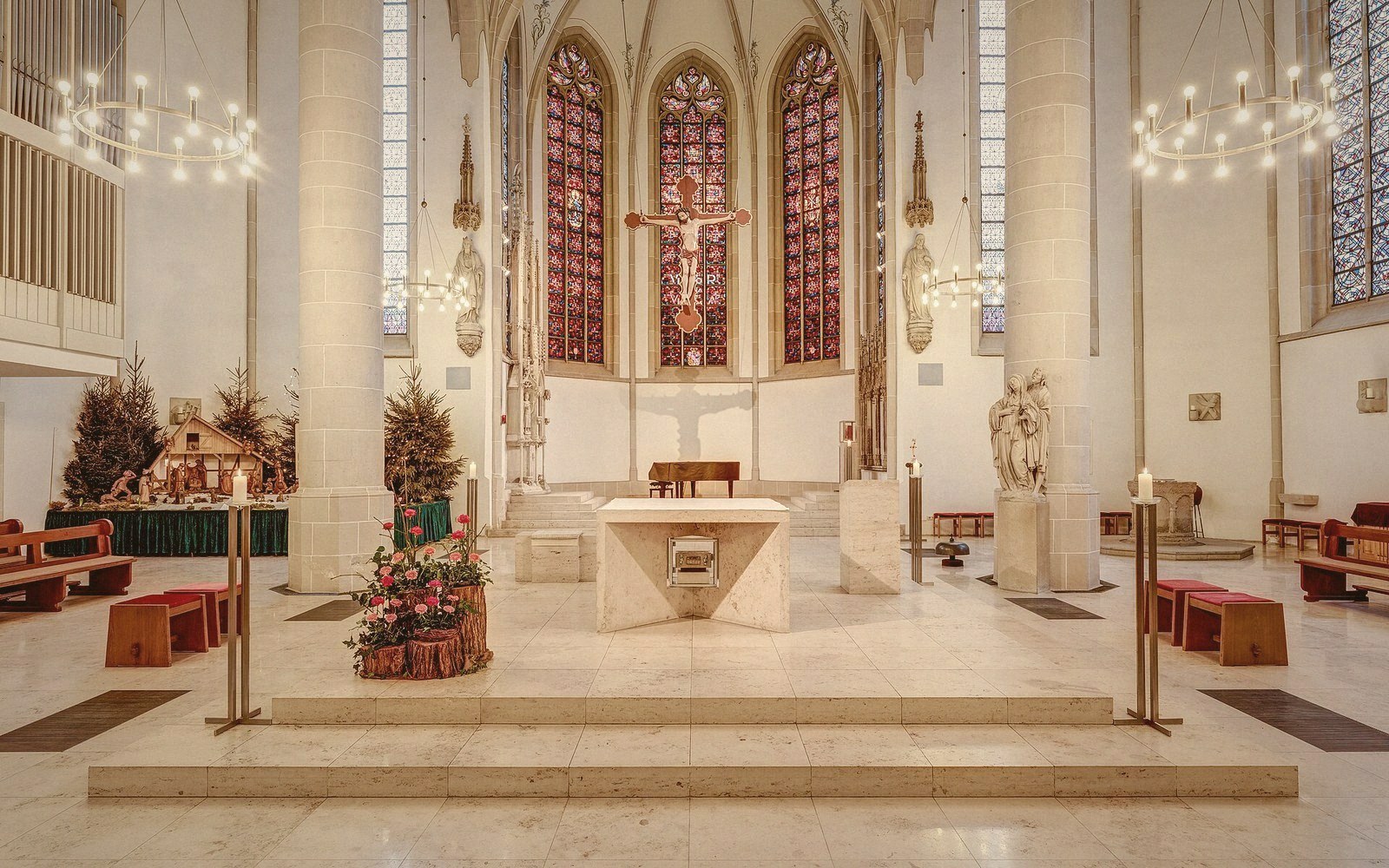 Gothic church altar with a crucifix and stained glass windows in the apse